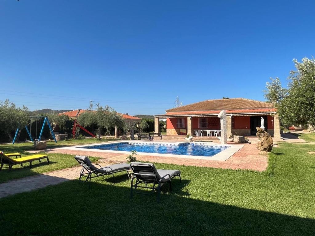 a yard with a pool with chairs and a house at La Estacada in Lora del Río