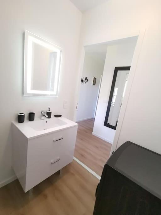 a white bathroom with a sink and a mirror at LE MEDITERRANEEN *T2 (40m²) *WIFI*PARKING PRIVE* in Lourdes