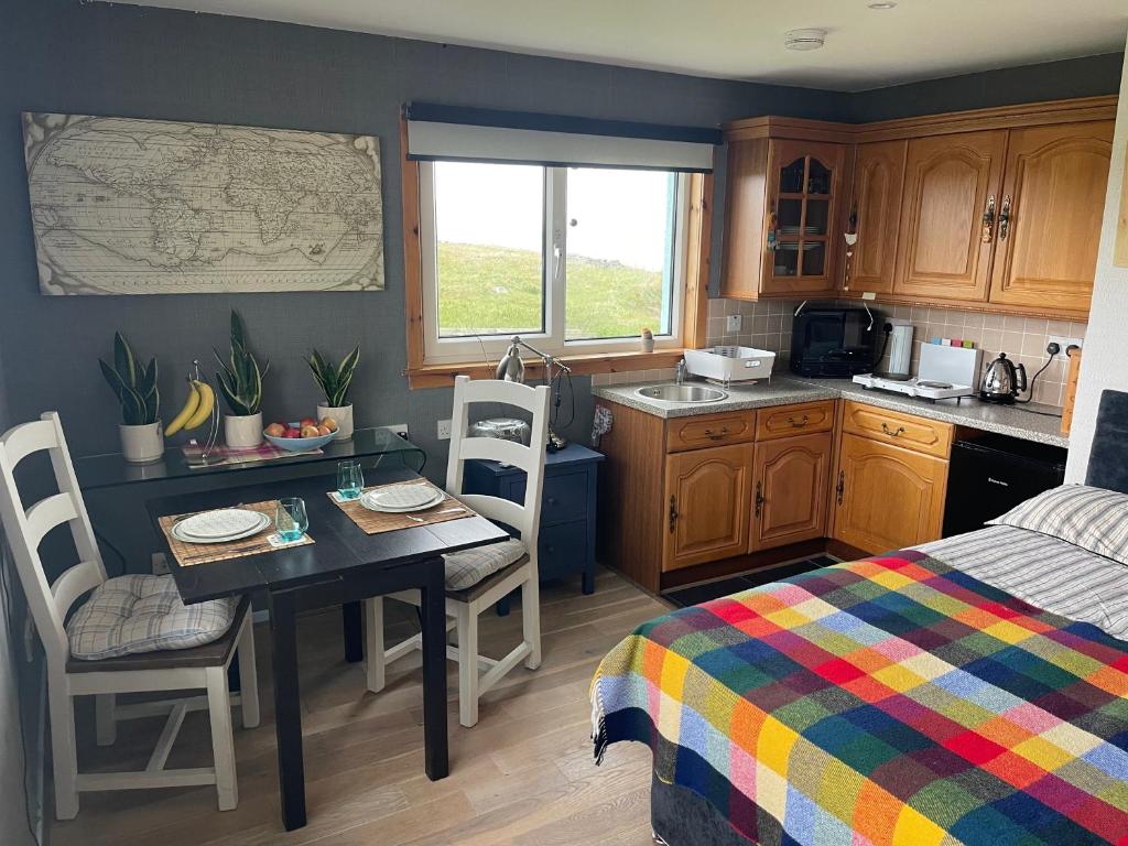 a small kitchen with a table and a bed at Music of the Sea- Isle of South Uist, HS8 5RF in Clachan