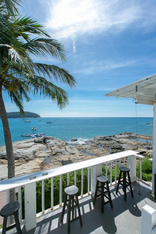 a balcony with chairs and a view of the ocean at Naiharn On The Rock Resort Phuket in Nai Harn Beach
