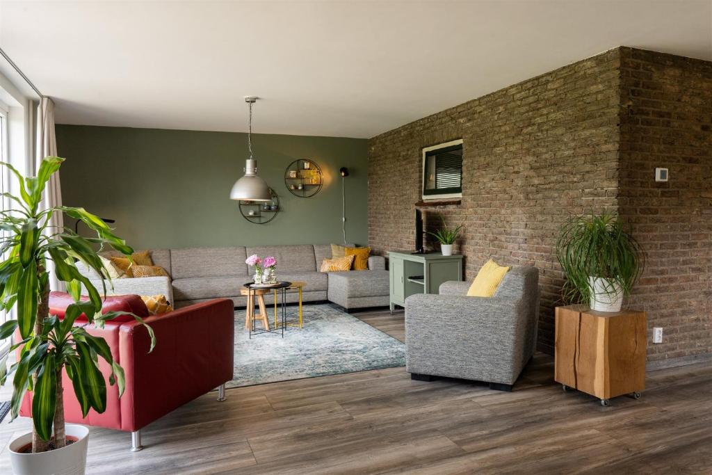 a living room with a couch and a brick wall at Vakantiewoning Le Garaazje in 's-Gravendeel
