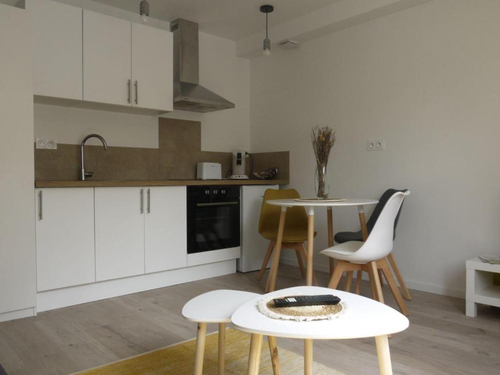 a kitchen with white cabinets and a table and chairs at Appartement, Mussidan in Mussidan