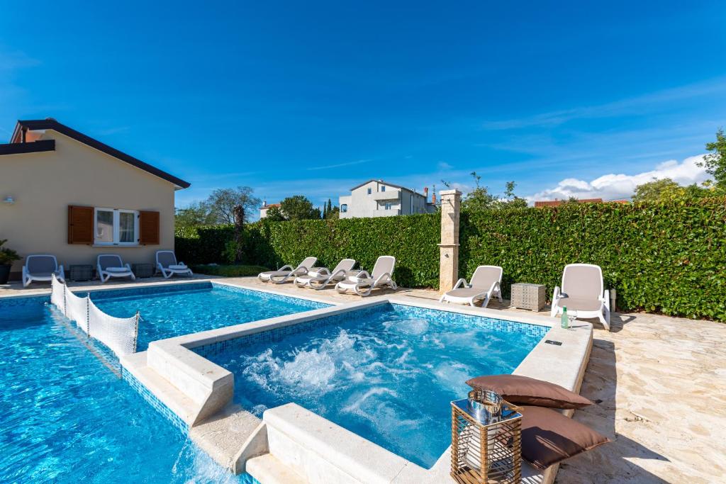 a swimming pool with lounge chairs and a house at Kastelir in Kaštelir