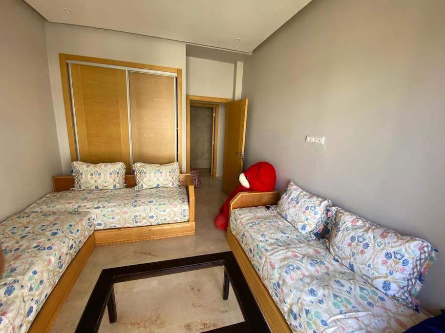 a small bedroom with two beds and a couch at Résidence avec piscine Kenz Mehdia in Kenitra