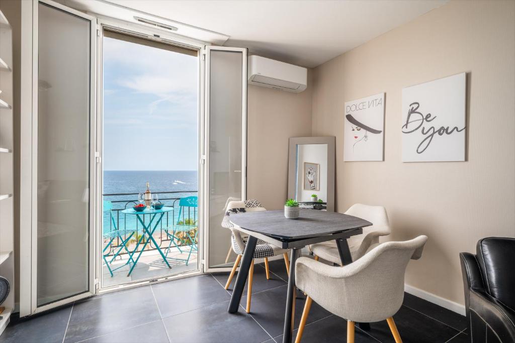 ein Esszimmer mit einem Tisch und Meerblick in der Unterkunft Le balcon de la baie des Anges in Nizza