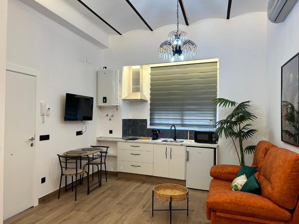 eine Küche und ein Wohnzimmer mit einem Sofa und einem Tisch in der Unterkunft Apartamentos Casa el Gorras in Córdoba