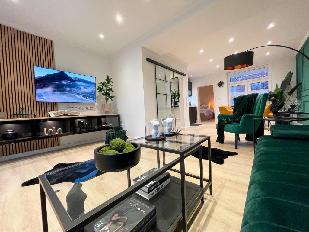 ein Wohnzimmer mit einem grünen Sofa und einem TV in der Unterkunft Ferienwohnung Domizil am Delft II Emden in Emden