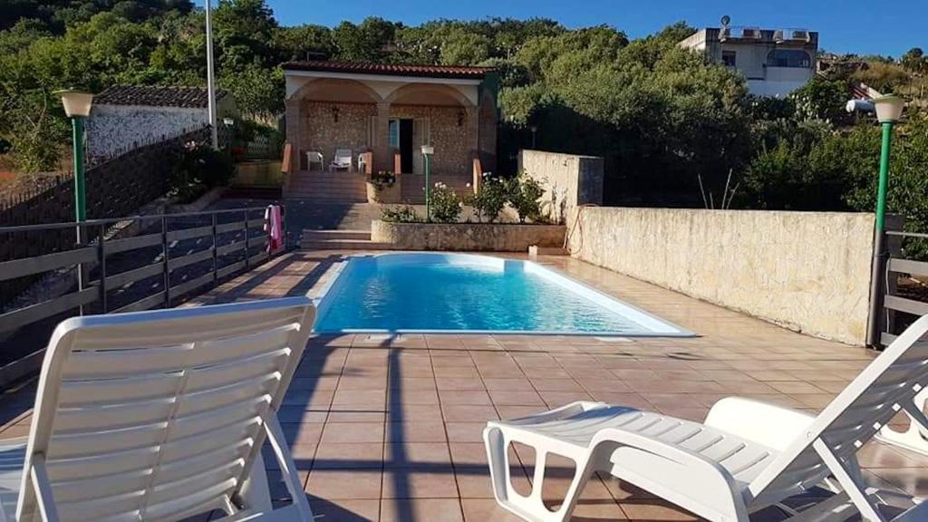 - une piscine avec 2 chaises et une maison dans l'établissement 3 bedrooms villa with private pool and wifi at Caccamo 9 km away from the beach, à Caccamo