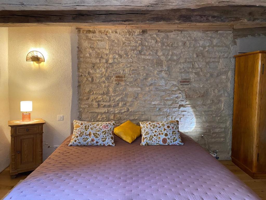 a bedroom with a bed with a stone wall at Moulin de la Rouchotte in Frétigney-et-Velloreille