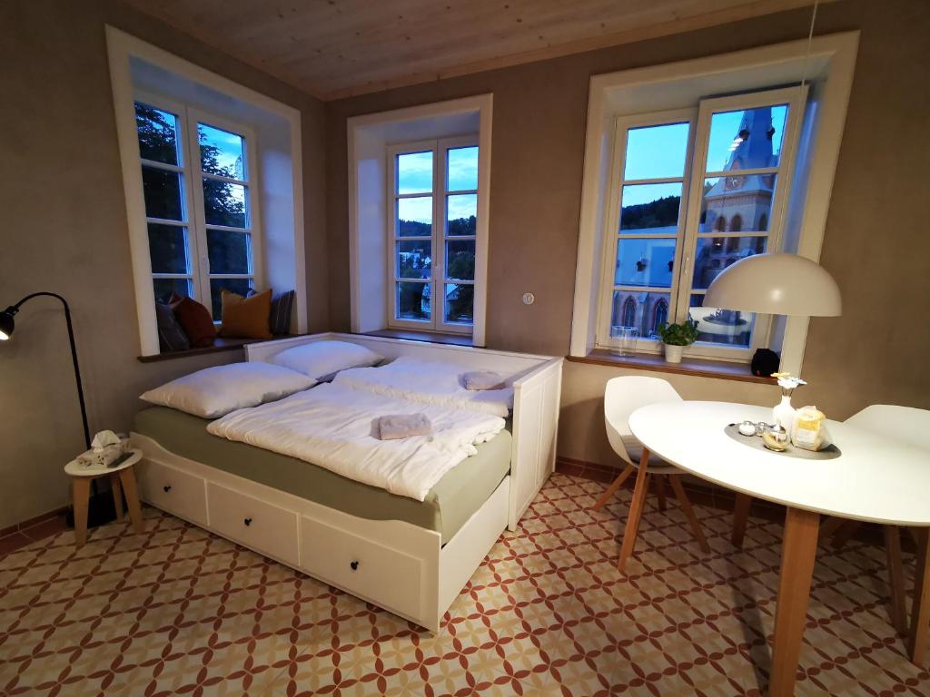 1 dormitorio con cama, mesa y ventanas en Vila Braun, en Horní Maršov