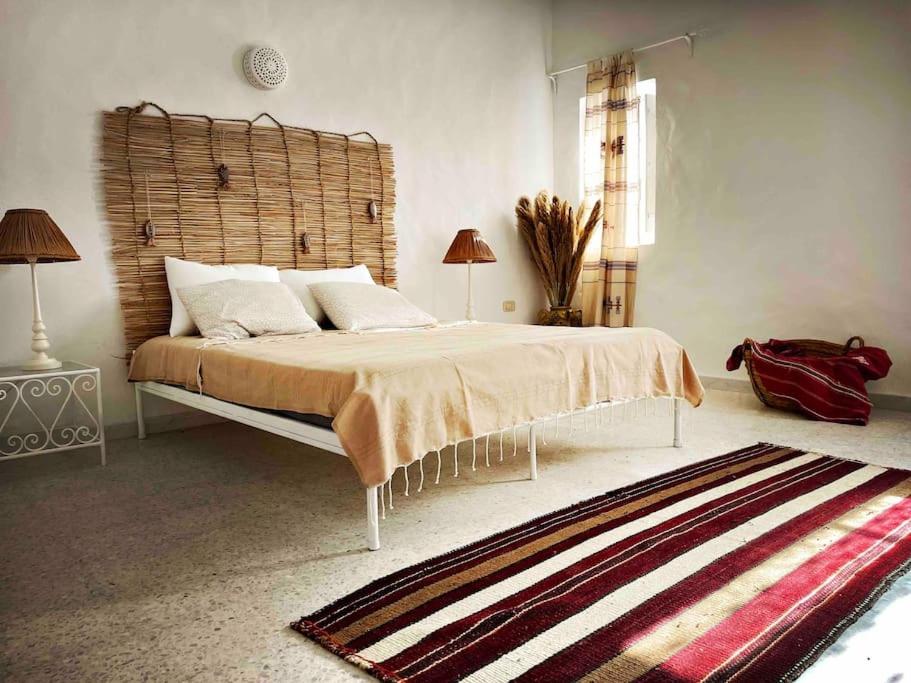 a bedroom with a large bed with a wooden headboard at Dar-dina-Total escapism in Djerba in Mezraya