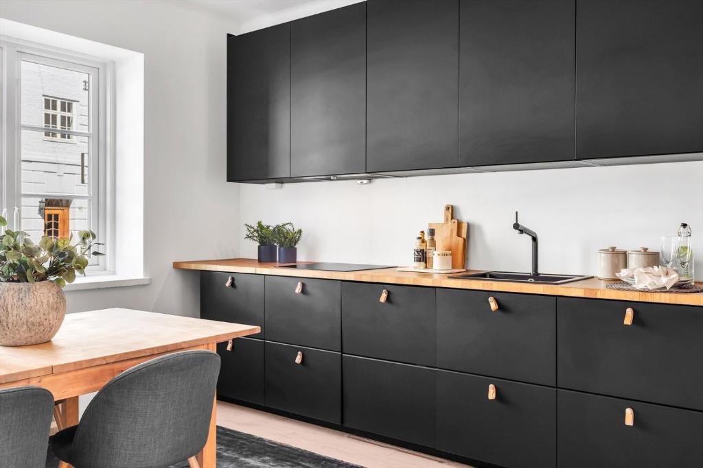 cocina con armarios negros y mesa de madera en Apartment in the best part of Oslo, en Oslo