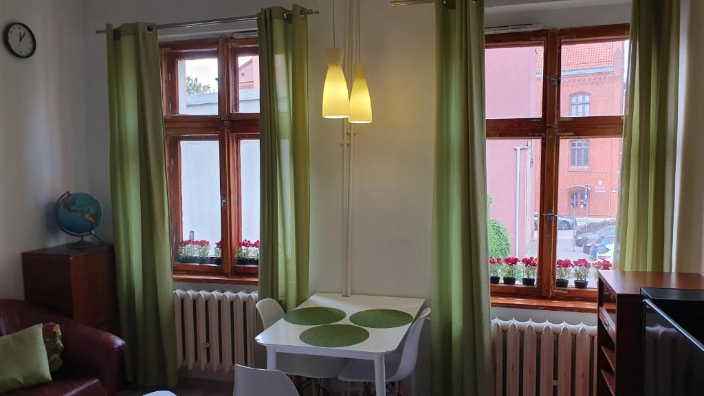 a room with green curtains and a table in front of a window at Apartament Olsztyn Centrum in Olsztyn