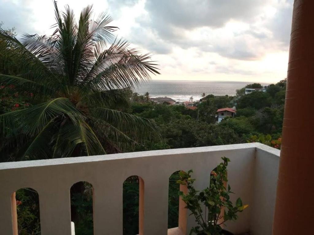 a balcony with a view of the ocean and a palm tree at Casa Blanca Zipolite, Dream House in Zipolite