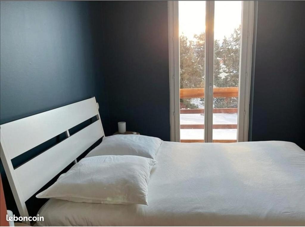 une chambre avec un lit blanc et une fenêtre dans l'établissement Appartement idéalement situé Font romeu, à Font-Romeu-Odeillo-Via