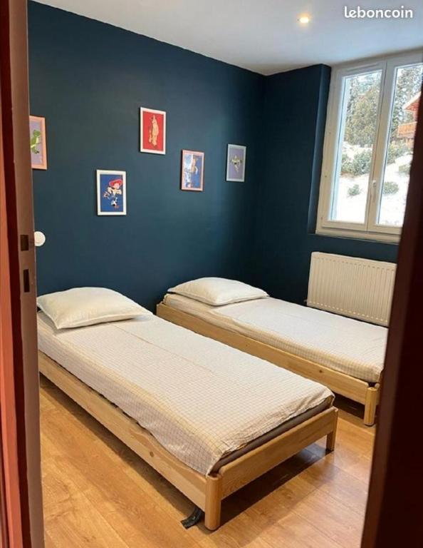 two beds in a room with a blue wall at Appartement idéalement situé Font romeu in Font-Romeu-Odeillo-Via
