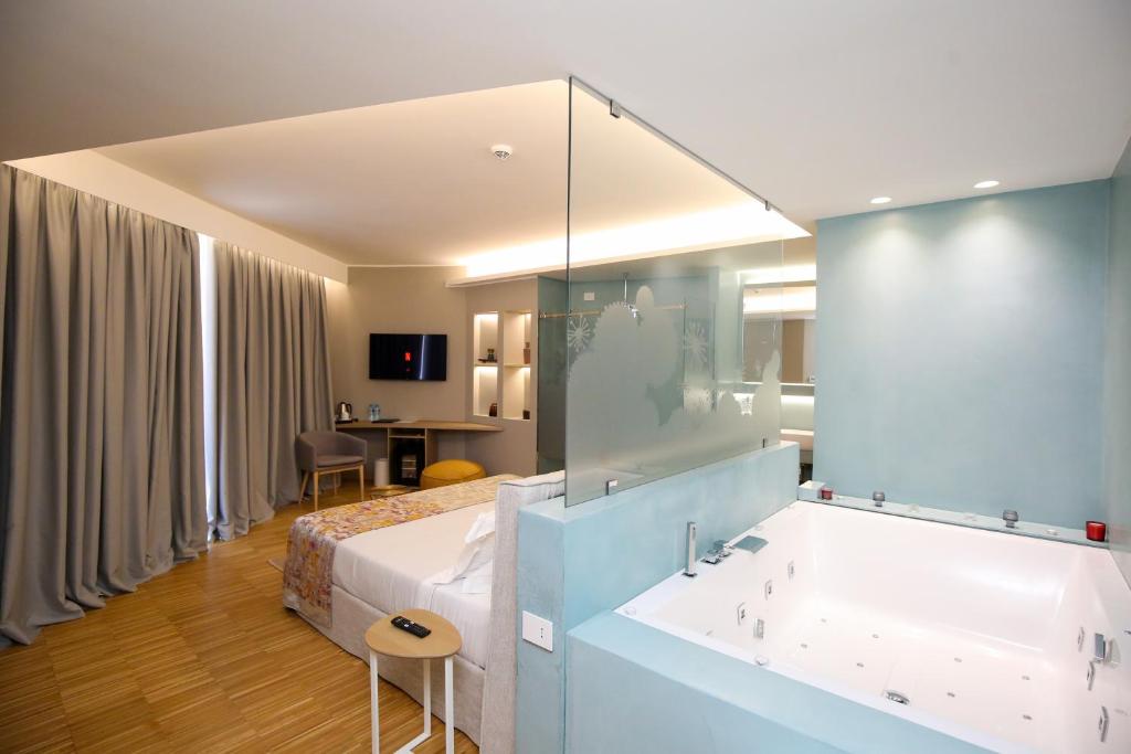 a hotel room with a bed and a bath tub at Priam Hotel Luxury Resort in Vlorë