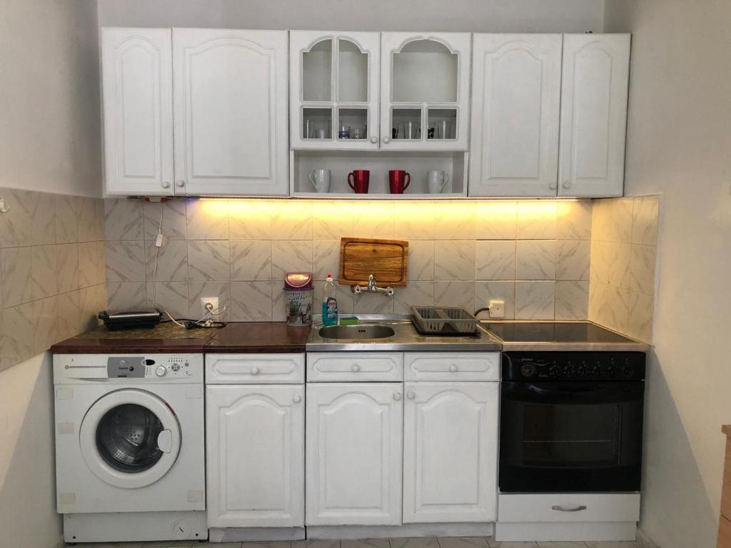 uma cozinha com armários brancos e uma máquina de lavar roupa em Гарсониера Жорката em Varna City