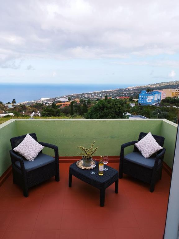 two chairs and a table on a balcony with the ocean at Casa Olini in Breña Alta