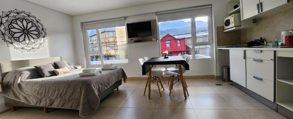 a bedroom with a bed and a table and a kitchen at Departamento Austral II in Ushuaia