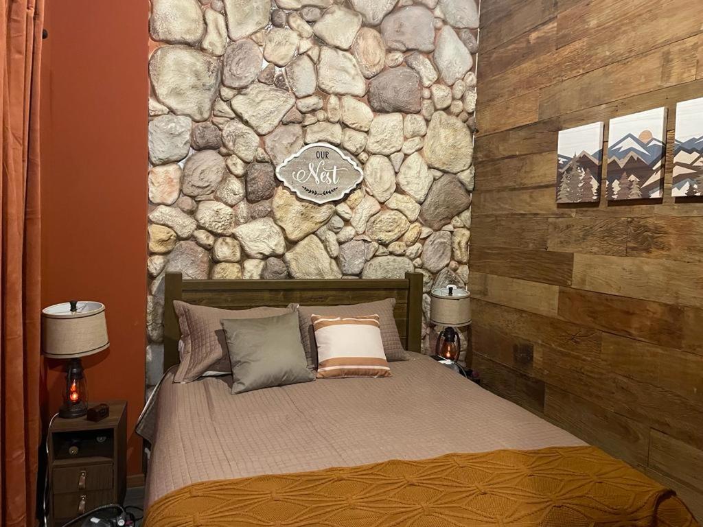 Cama en habitación con pared de piedra en Chalé Colorado Vibe en Camanducaia