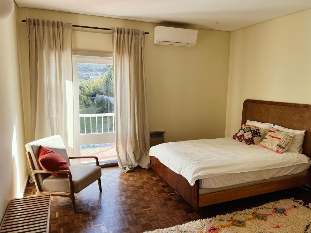 een slaapkamer met een bed, een stoel en een raam bij Casa Veiga in Colares