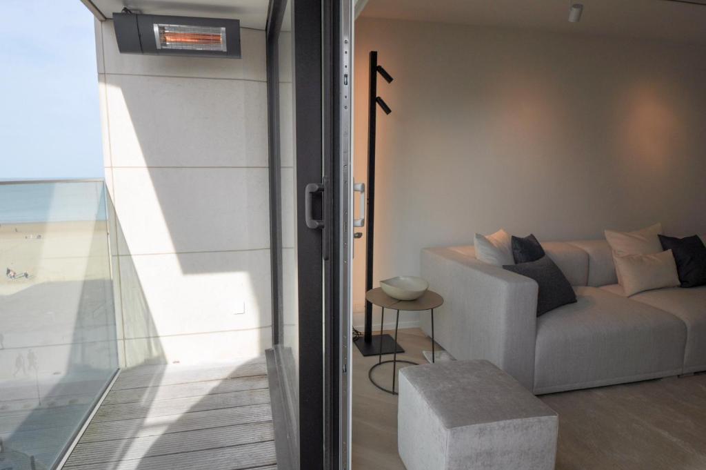 a living room with a couch and a table at Premium modern flat at Zoute Beach 2 bicylcles included in Knokke-Heist