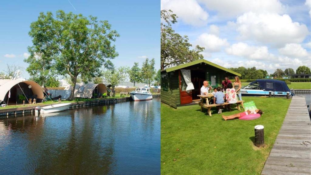 アールスメールにあるCamping Recreatiepark Aalsmeerの川の横の芝生に座る人々