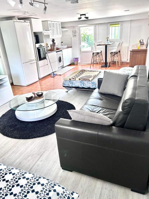 un salon avec un canapé noir et une cuisine dans l'établissement La Perle, proche Roissy CDG, Paris, Parc asterix, Disney, à Moussy-le-Vieux