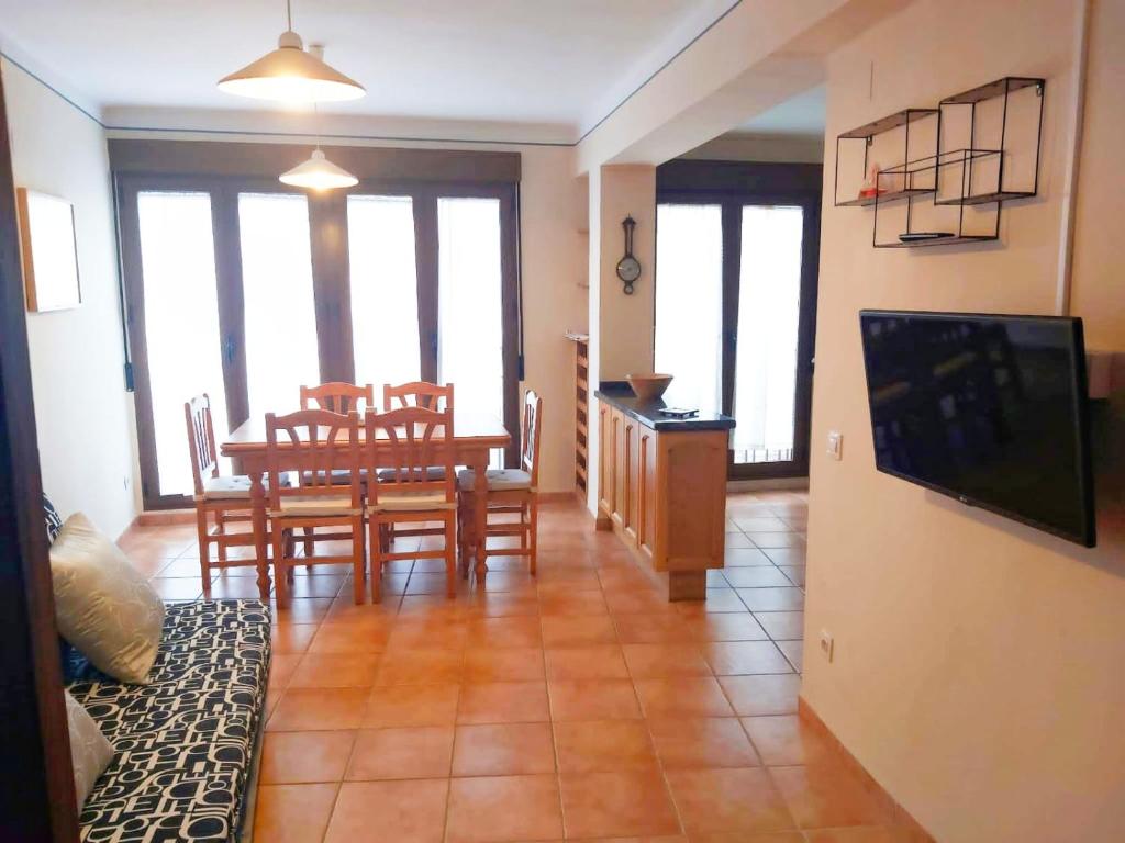 ein Wohnzimmer mit Tisch, Stühlen und Fernseher in der Unterkunft Ca l'Èndula in Lucena del Cid