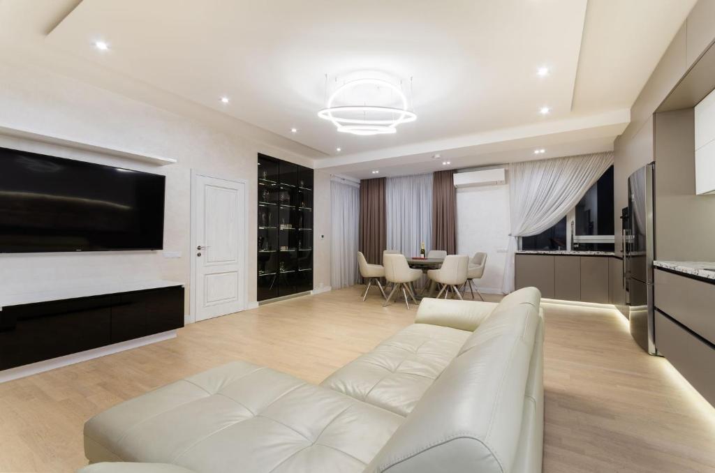 a living room with a white couch and a television at Luxury apartment close to the city centre in Chişinău