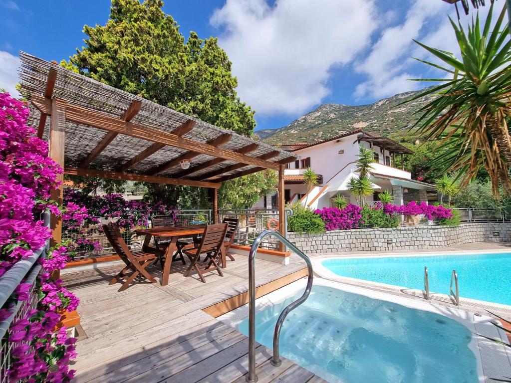a patio with a table and chairs next to a swimming pool at Eco Hotel Montemerlo in Fetovaia