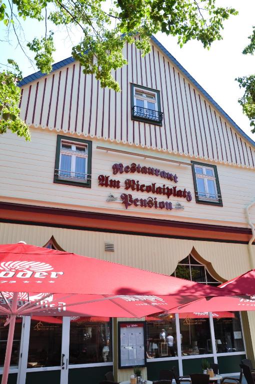 un restaurant avec un parasol rouge en face d'un bâtiment dans l'établissement Pension "Am Nico", à Wernigerode