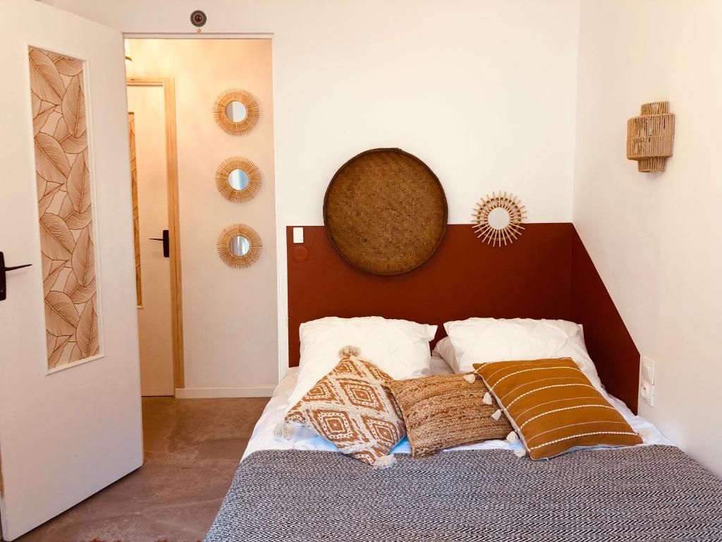 a bedroom with a bed with a brown headboard and pillows at CASA DAHLIA - Charmant appartement équipé avec grande terrasse in Marseillan