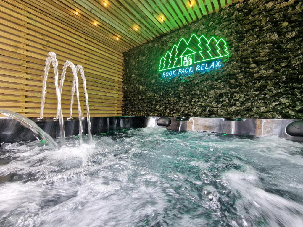 Bowness - 3 Bed - Hot Tub House في باونيس أون وينديرمير: حوض استحمام ساخن بالماء أمام علامة خضراء