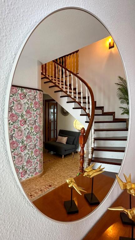 a mirror reflecting a living room with a spiral staircase at Casa Rural Las Camelias in Herrera del Duque
