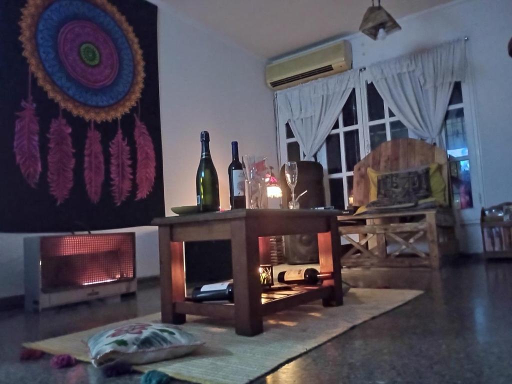 a living room with a table with two bottles of wine at Hostel AGUS !!! in Guaymallen