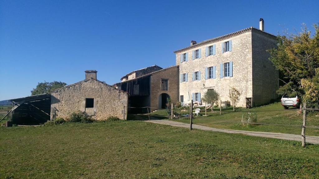 un gran edificio de piedra con un campo de césped al lado en Le Clos Saint Georges, en Donnazac