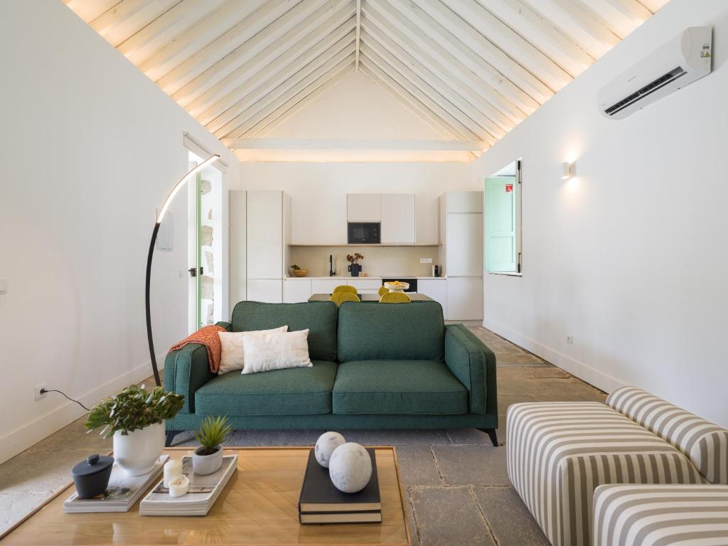 ein Wohnzimmer mit einem grünen Sofa und einer Küche in der Unterkunft Agroturismo Suites Hacienda los Olivos in Santa Brígida