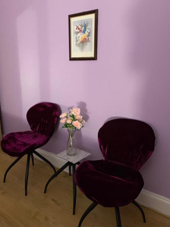 a room with two chairs and a table with a vase of flowers at Your Perfect HomeStay in Ilford
