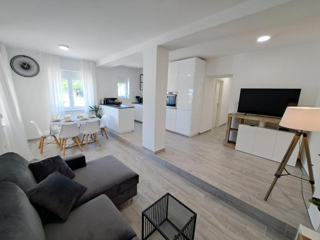 a living room with a couch and a tv and a kitchen at Holiday house SeaDream - 50 meters from the sea in Brodarica