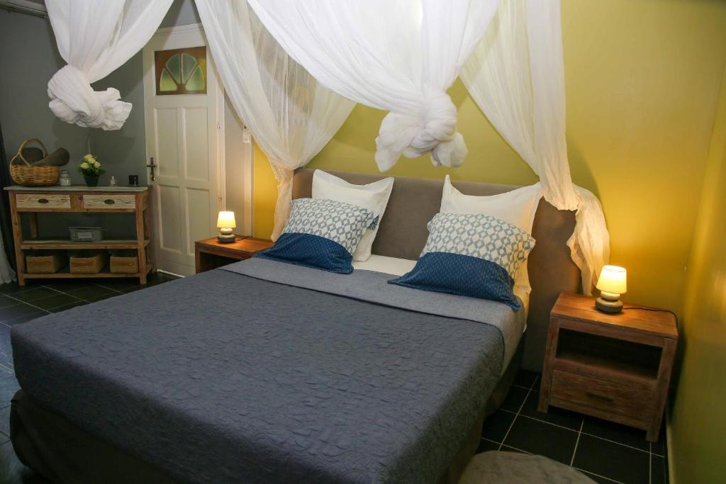 LES NUITS GALANTES MANDEVILLA MAISON PRIVÉE AVEC JACUZZI في سانت فرانسوا: غرفة نوم مع سرير ذو أغطية زرقاء ومخدات زرقاء