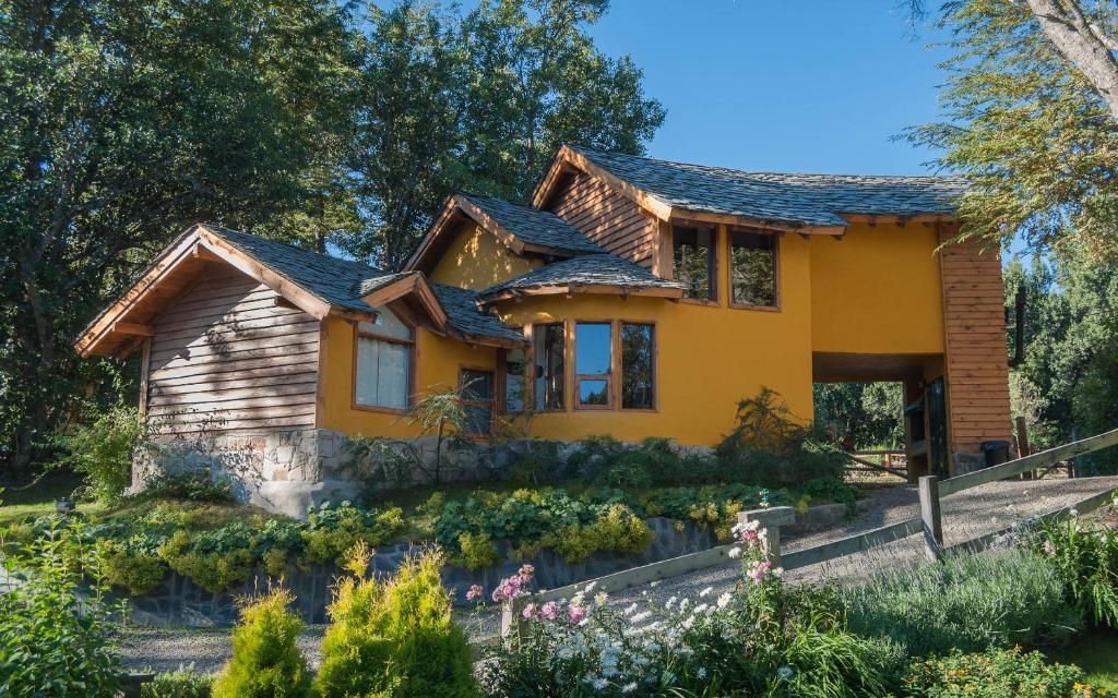 uma casa amarela com um jardim em frente em Cabañas Lelikelen em Villa La Angostura