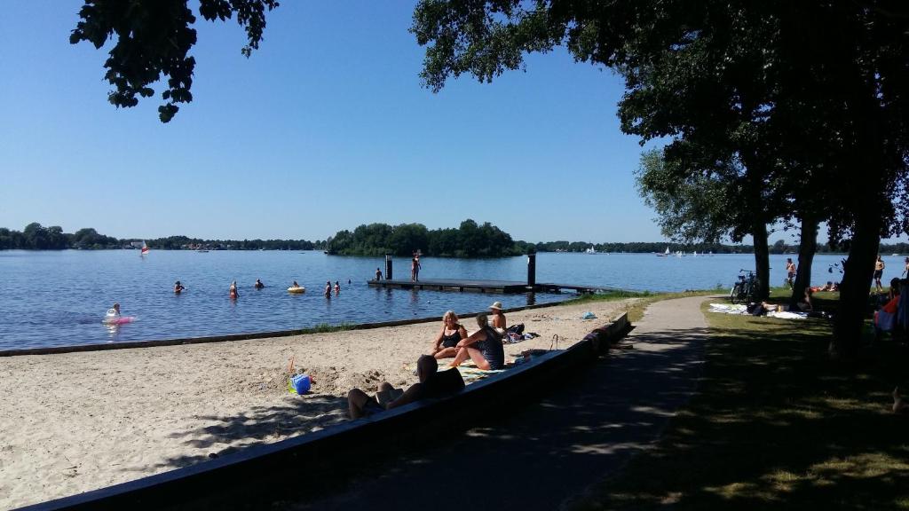 a group of people sitting on a beach near the water at Drenthse-Groninger landschap in Haren