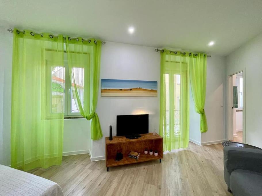 sala de estar con cortinas verdes y TV en Casa da fortaleza en Sesimbra