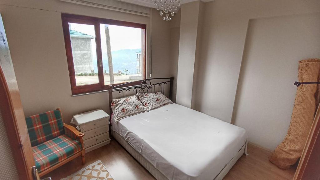 - une chambre avec un lit, une fenêtre et une chaise dans l'établissement Tepedeki Ev, à Akcaabat