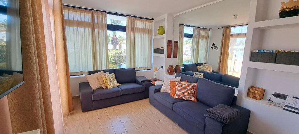 un soggiorno con 2 divani blu e finestre di El Gueco Holiday Apartment a Costa Teguise
