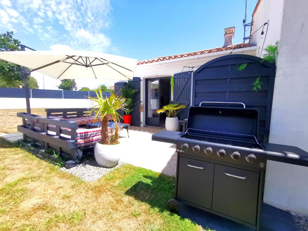 un barbecue avec un banc et un parasol dans l'établissement La villa du Veillon, à Talmont-Saint-Hilaire