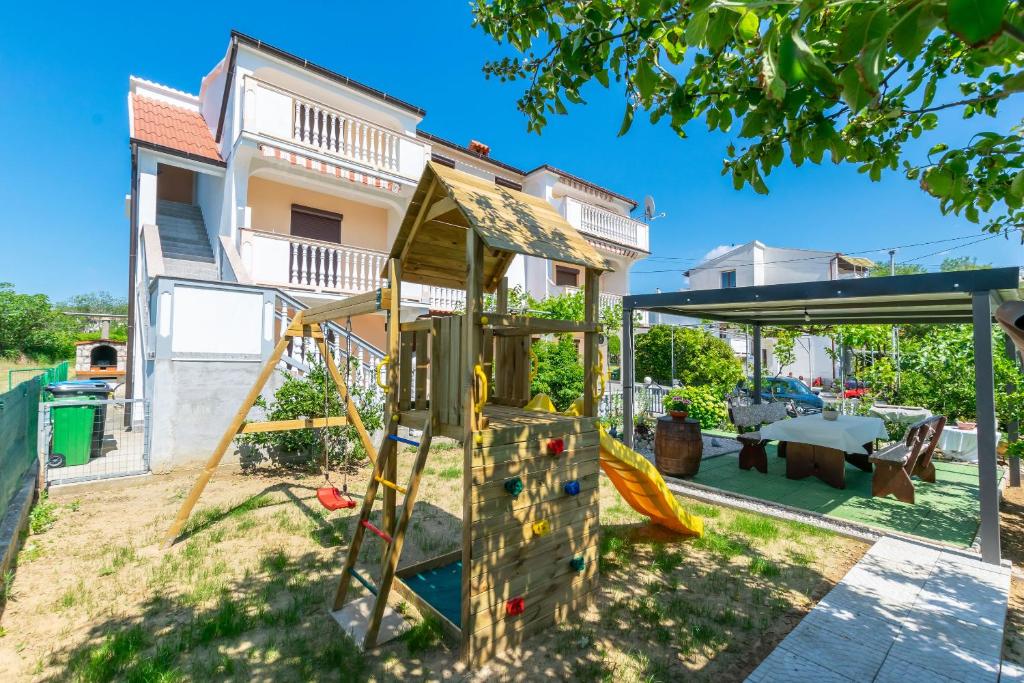 a house with a playground in the yard at Apartment Branko in Lopar