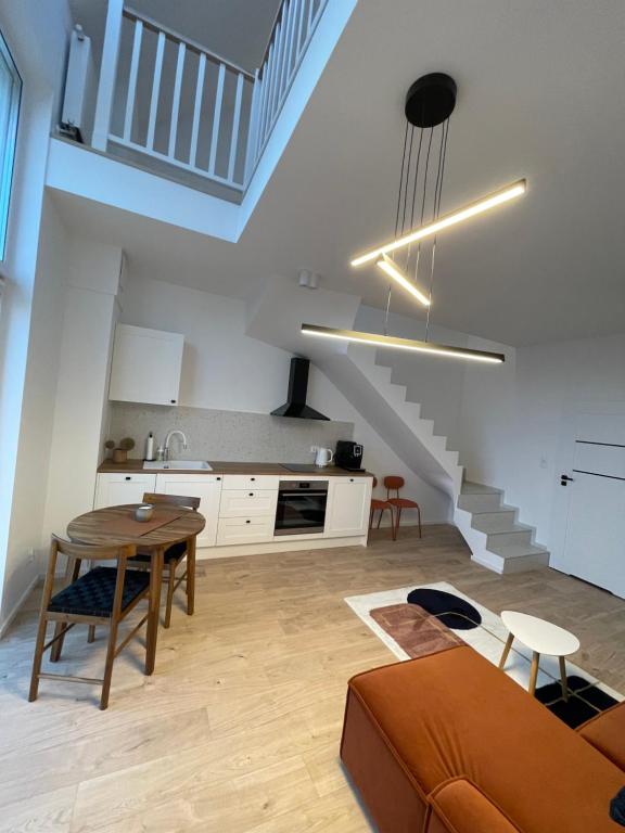 sala de estar con mesa y cocina con escaleras en Porto Mare Apartament Mechelinki, en Mechelinki